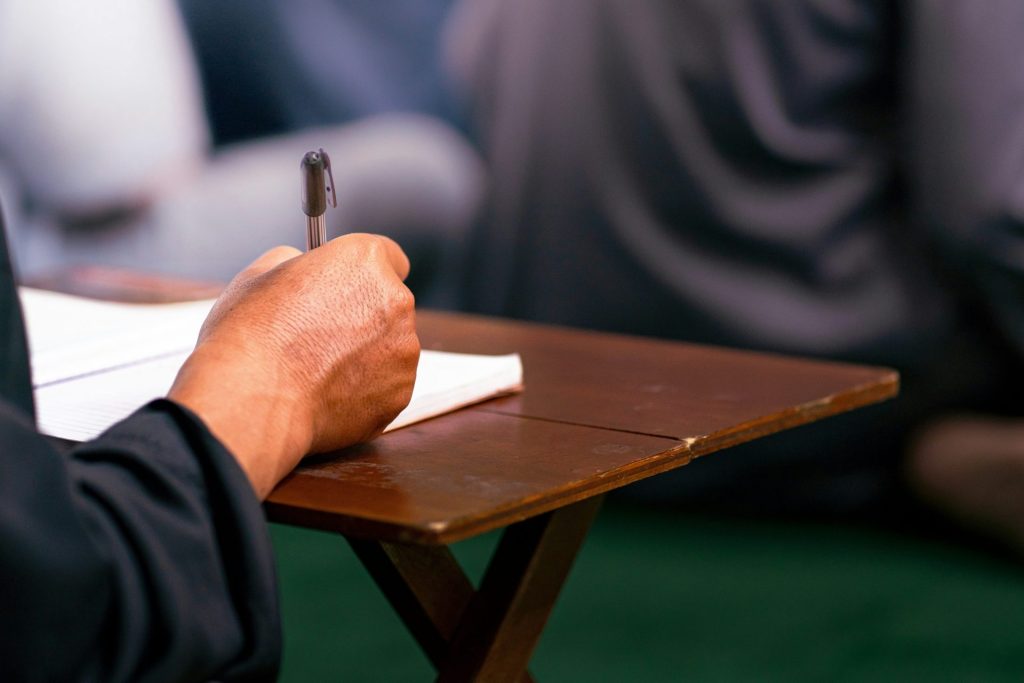 A person sitting at a desk writing on a piece of paper